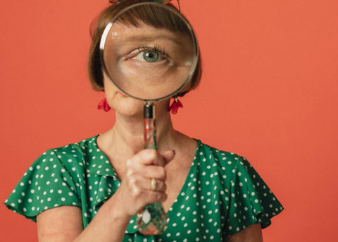 Vrouw die door een vergrootglas naar de camera kijkt